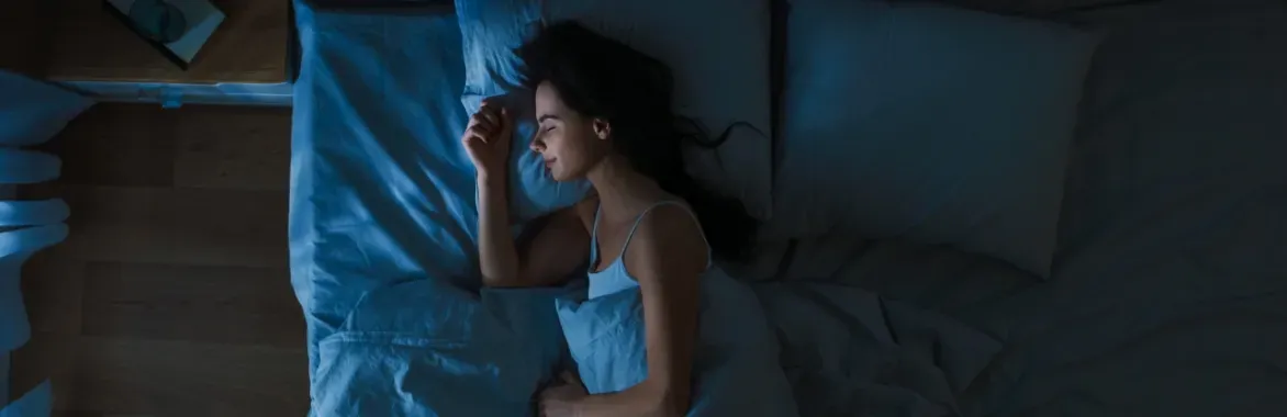 woman in blue tanktop sleeping soundly in bed